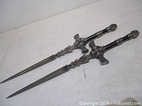 Two matching steel swords side by side displaying overall design
