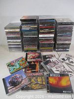 Stacks of jewel-case CDs with several laid out showing covers