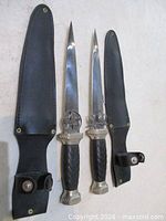 Two athames alongside sheaths showing handles, blades, guards