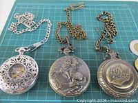Front view of three pocket watches showing covers and chains
