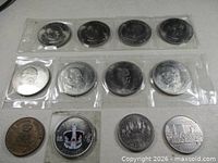 All coins and medallion laid out showing obverse designs in two plastic strips and loose pieces