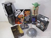 Group shot of all boxed items, Yoda figure, coin album, mugs, puzzle ball