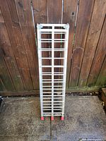 Ramp folded standing vertically against fence showing red tips