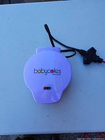 Closed purple Babycakes cake pop maker showing indicator lights and branding