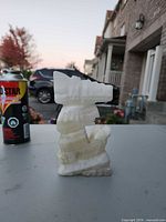 Front view of alabaster tiki figurine beside reference object