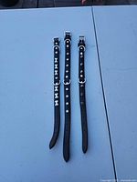 Three black leather collars aligned on table showing full length and decorations