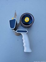 Oblique top view showing dispenser handle, tape roll and yellow tab