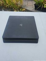 Top angled view of Sony PS4 Slim console showing PlayStation logo and overall condition