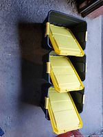 Three stacked Sterilite totes showing black bodies and yellow lids