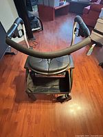 Front view of black rollator showing seat, backrest, basket, wheels