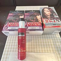 Front view of all four packaged items: two Schwarzkopf Keratin Color 4.7, one L’Oreal Feria 36, one TRESemmé spray