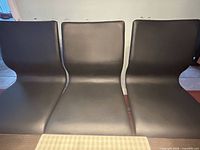 Front view of three black faux leather dining chairs
