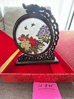 Screen assembled in stand inside open red brocade box