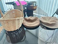 Wicker basket beside two corduroy hats on glass table