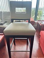 Full view of bar stool showing leather seat/back, cut-out backrest, wood legs