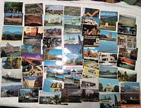Wide view showing bulk of approximately 70 assorted vintage postcards laid flat