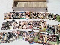 Open cardboard box showing rows of upright football cards with sample cards spread in front.