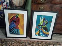 Two framed Ivey Hayes prints leaning against furniture