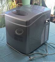 Front three-quarter view of Magic Chef ice maker with lid closed and power cord visible