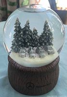 Front view of snow globe showing cars, trees, base logo