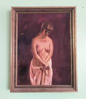 Framed oil painting showing standing nude female against dark background, wood frame visible