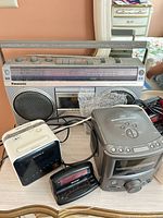 Group shot of Panasonic boombox and four clock radios