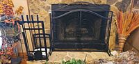 fireplace screen, log holder and tool set displayed in front of stone hearth