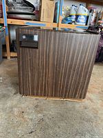 Front and side view of GE SC25K compact refrigerator showing woodgrain finish and handle with logo