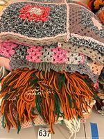 Stack of multiple crocheted throws with visible granny square and fringed designs