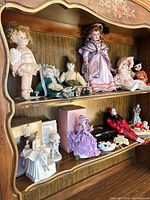 Full shelf showing upper and lower levels of dolls and figurines