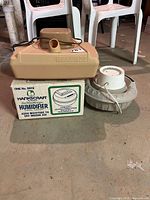 Three humidifiers grouped together; Hankscraft boxed, DeVilbiss beige unit on top, Proctor-Silex round gray unit beside