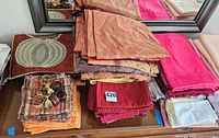 Stacked napkins, tablecloths, placemat, napkin rings on dresser