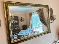 Front view of rectangular mirror showing ornate gold frame and reflection