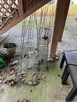 Stacked metal tomato cages leaning under deck, showing overall quantity and form