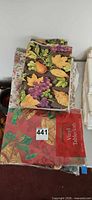 Stack showing harvest fruit cloth and sealed red holiday bells vinyl package