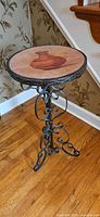 Full view of the accent table showing round top and scrolled wrought iron base