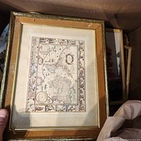 Gold-framed map print held for view
