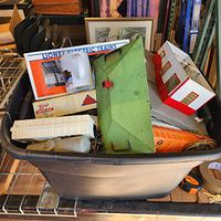 Overall view of plastic bin with Lionel station, mug, cars and accessories