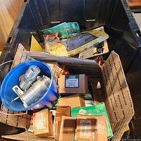 Overview of black bin, blue pail with couplings, assorted boxed hardware