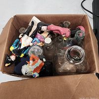 Overview of box showing assorted figurines and glass bottles