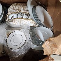 Open box showing stacked dinnerware and fabric storage case