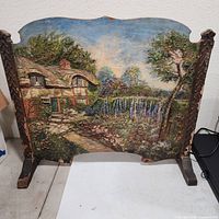 Front view showing painted cottage landscape and carved wood frame
