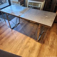 Table fully unfolded showing metal surface and folding legs