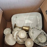 Box view showing starburst platter, bowls, plates, metal goblet