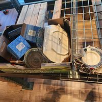 Box containing casserole dish, blue boxes, heat diffuser and stacked plates