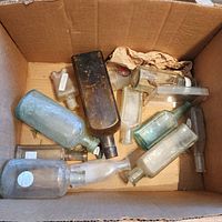 Overview of box containing assorted clear, aqua and amber glass bottles