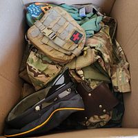 Overview of box with tactical pouch, camouflage clothing, service cap, leather piece