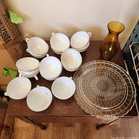 Stacked Pyrex cups, amber vase, clear pressed platter on table