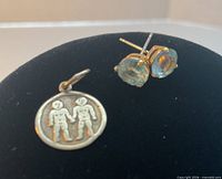 Stud earrings and charm displayed together on black backing