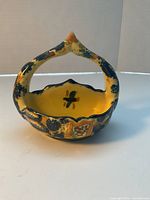 Front view showing arched handle, yellow glaze, blue sponge decoration, floral motif